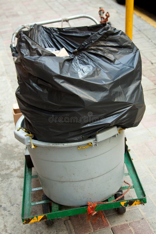 A wheelie-bin with a black plastic trash bag stock images