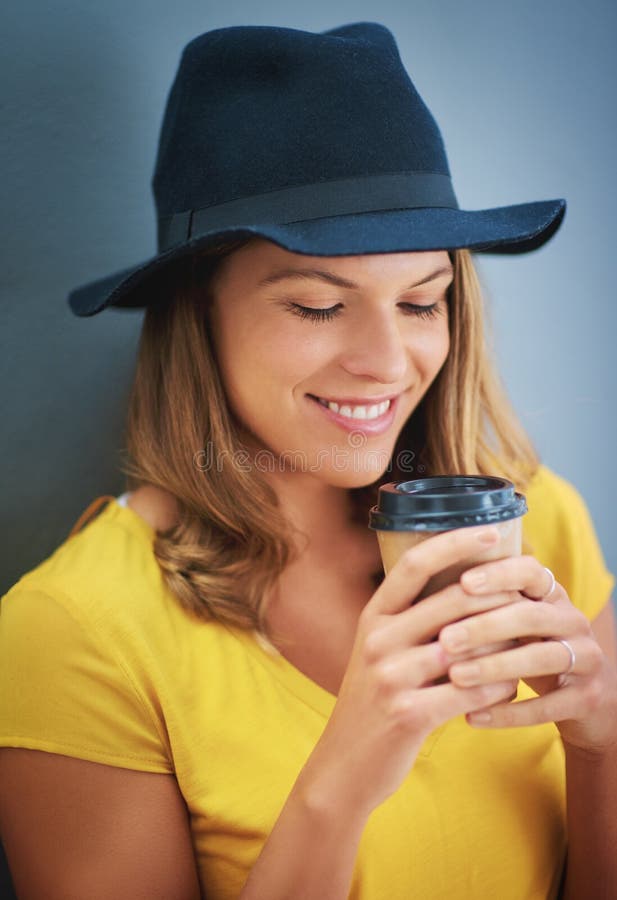 De mujer joven bebiendo extraer café contra gris.