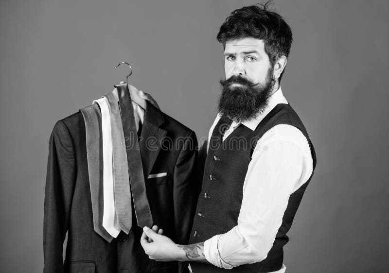 Which tie should I wear. Bearded man matching neck tie color to coat. Brutal hipster holding colorful tie collection and suit jacket. Choosing a perfect tie.