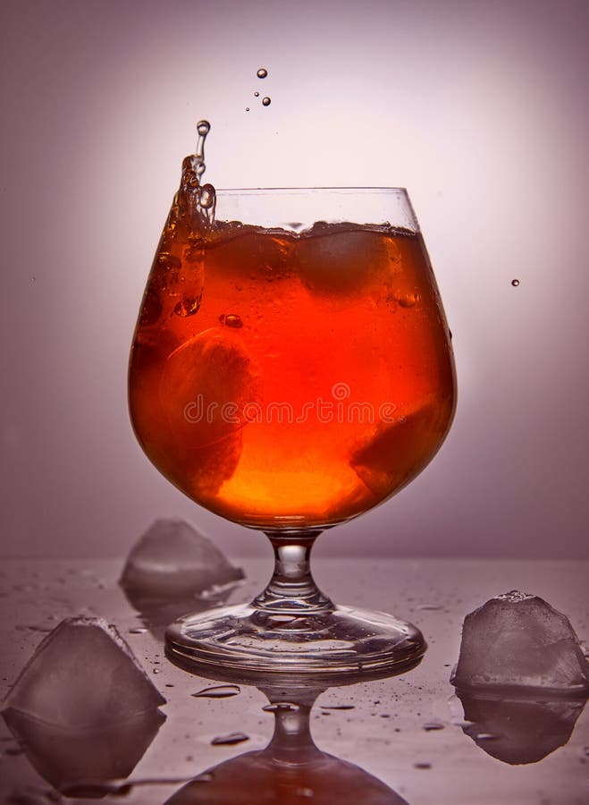 Whiskey, bourbon, eau-de-vie fine ou cognac avec de la glace sur un fond rose image libre de droits Whiskey, bourbon, eau-de-vie fine ou cognac avec de la glace sur un fond rose image libre de droits