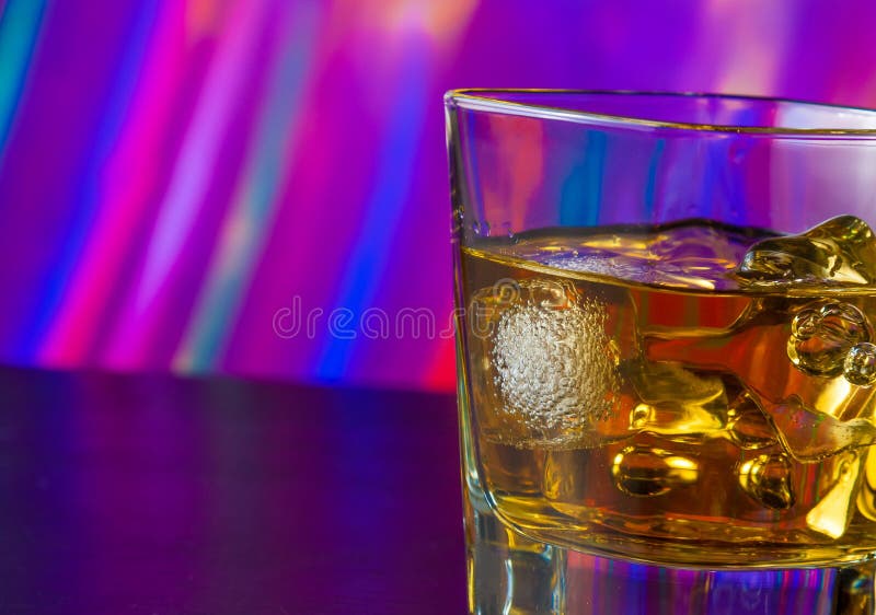 Whiskey Glass with Ice on Bar Table on Warm Atmosphere Stock Photo