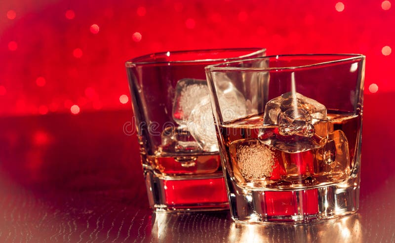 Whiskey glass with ice in front of empty whiskey glass on red bokeh. Bokeh whiskey stock images, royalty-free photos and pictures