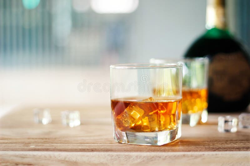 Whisky en dos vidrios y botellas en un fondo de madera de la tabla imágenes de archivo libres de regalías Whisky en dos vidrios y botellas en un fondo de madera de la tabla imágenes de archivo libres de regalías
