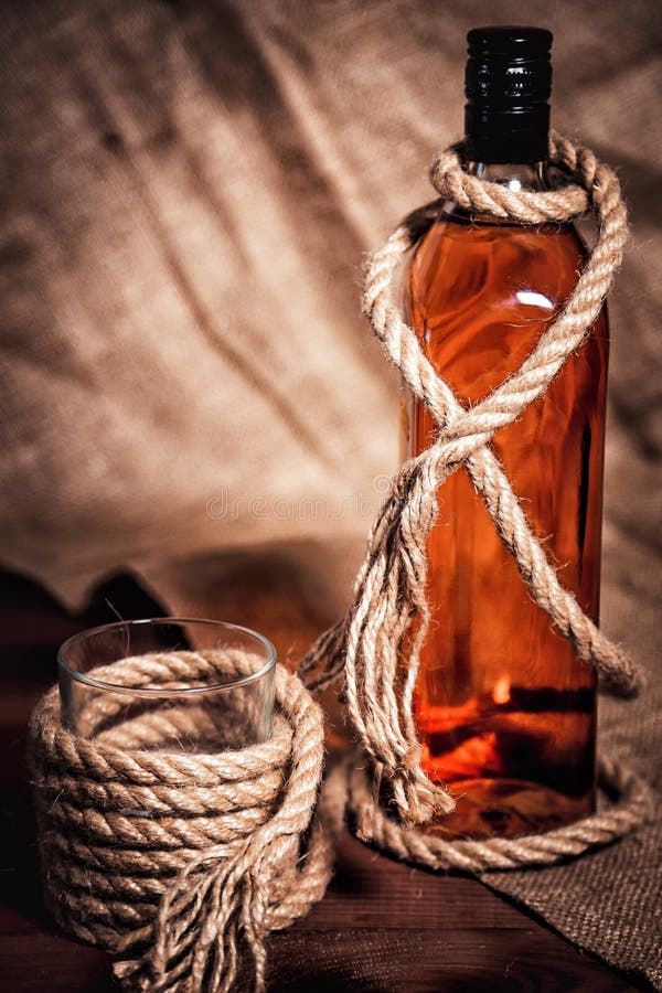 Whisky Glass with Ice, a Bottle of Whiskey and a Rope Stock Photo