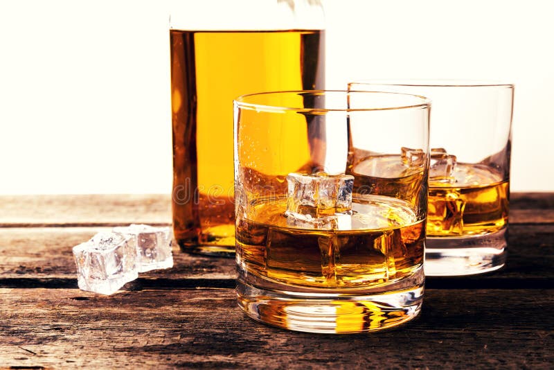 Whiskyglazen en fles op houten lijst tegen witte backgro stock fotografie Whiskyglazen en fles op houten lijst tegen witte backgro stock fotografie