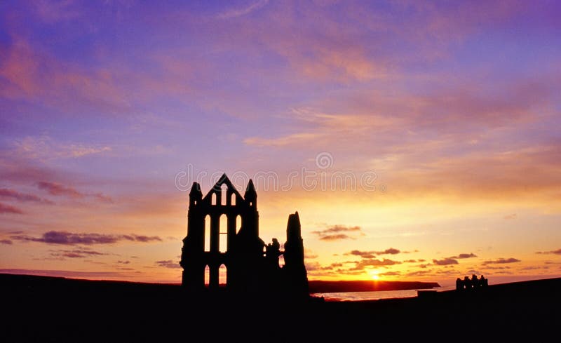 Ruiny opatství Whitby v North Yorkshire, osvětlené západu slunce nad Severním mořem.