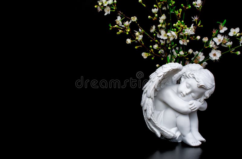 White angels statue with white flowers on black background