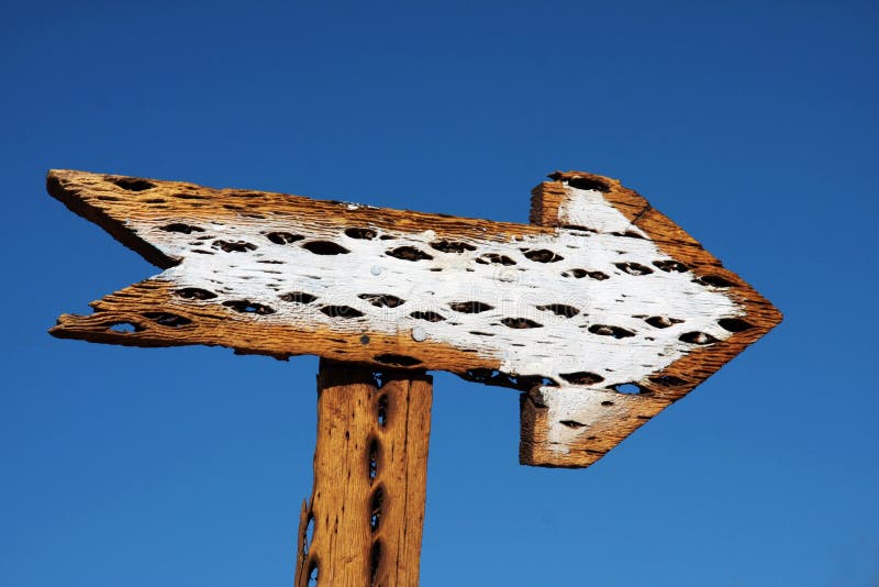 White wooden arrow on a blue sky in the desert. White wooden arrow on a blue sky in the desert