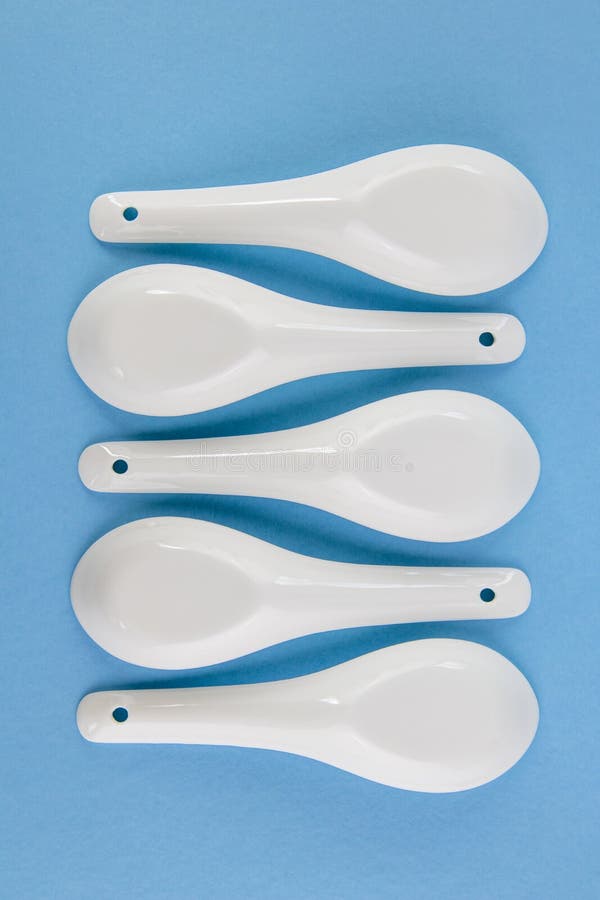 White Asian style spoons arranged in geometric pattern on blue background royalty free stock photography White Asian style spoons arranged in geometric pattern on blue background royalty free stock photography