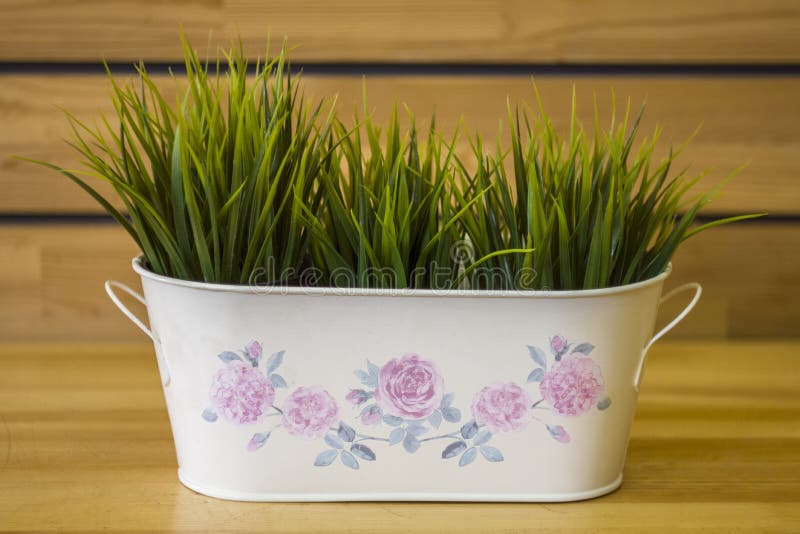 White basket with fresh bright green grass on a blurred yellow background of the table and wall stock image White basket with fresh bright green grass on a blurred yellow background of the table and wall stock image
