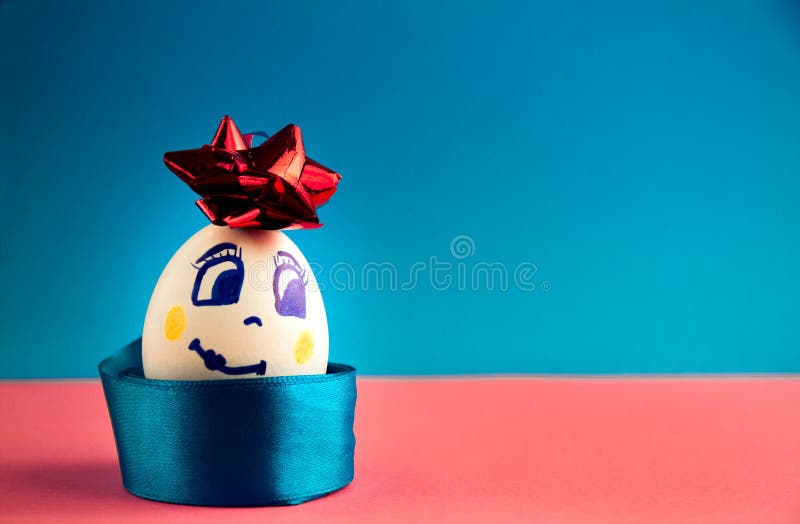 White. beautiful smiling egg with bow on pink and blue background, close-up stock images White. beautiful smiling egg with bow on pink and blue background, close-up stock images