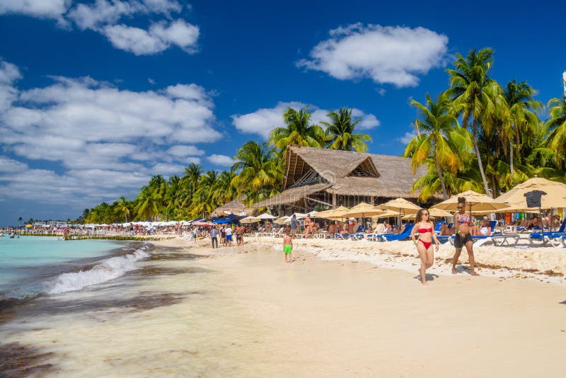 White and black girl ladies walking along the beach with umbrellas, bungalow bar and cocos palms, turquoise caribbean sea, Isla