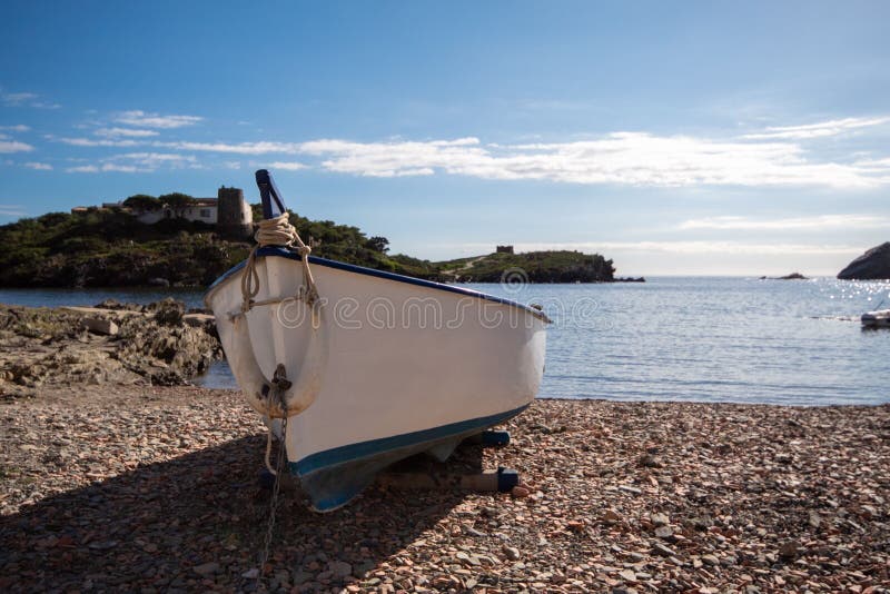 White And Blue Boat Parked On The Stones Of One Of The Small Beaches Of The Catalan Town Of