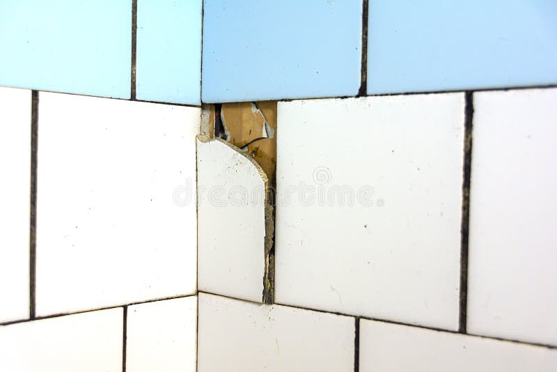 White and blue tiles on the wall. Old and broken tiles require replacement. Abstract background