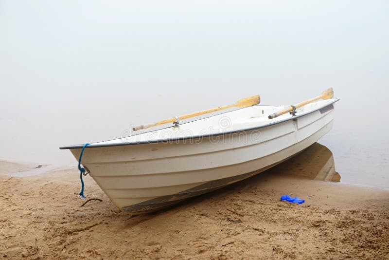 White boat on the shore misty morning