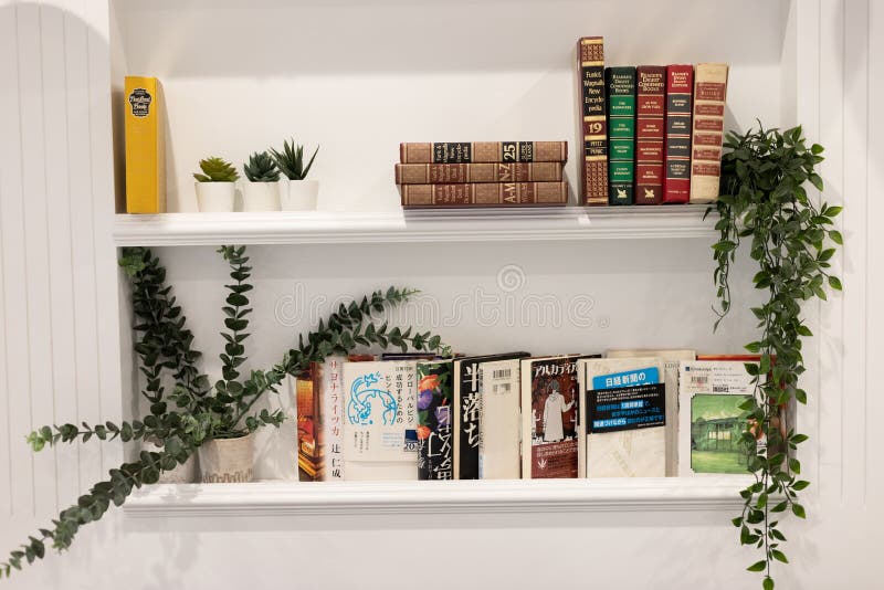 The White Bookshelf Has Books And Decorated With Fake Trees