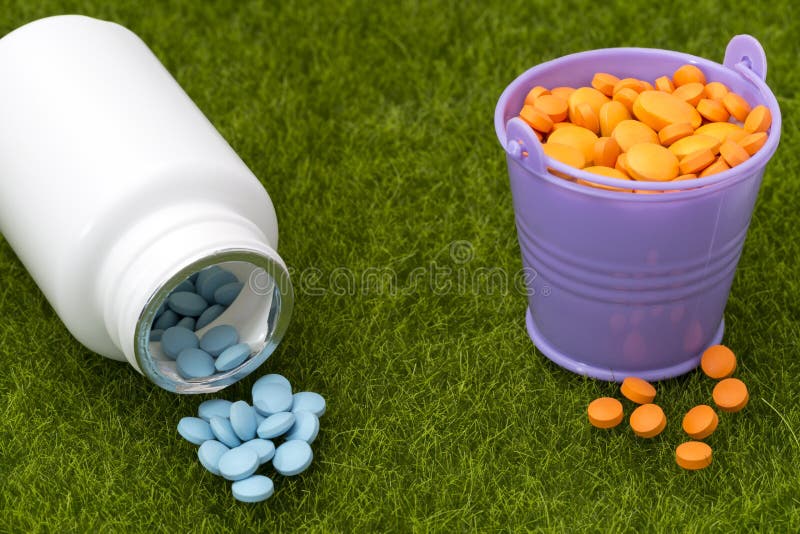 White bottle of blue pills and buckets filled with orange tablets