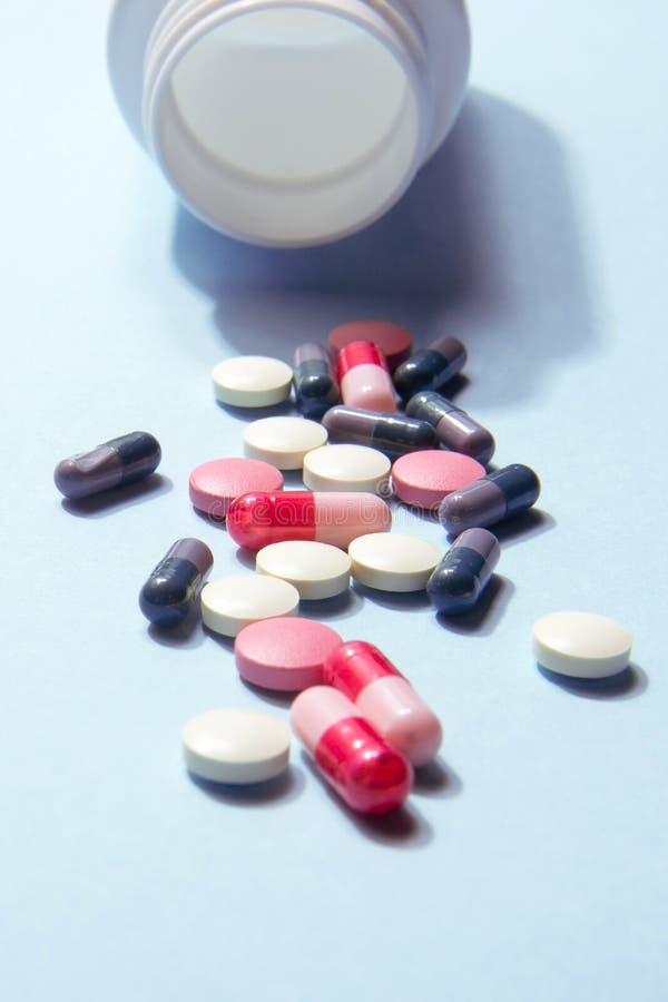White bottle of vitamin tablets and capsules on a blue background. Dietary supplements