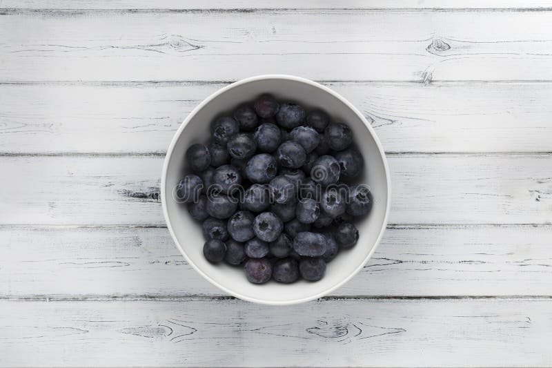 A white bowl full of delicious fresh Blueberries, shot on a distressed white wooden background, with copy space stock images A white bowl full of delicious fresh Blueberries, shot on a distressed white wooden background, with copy space stock images