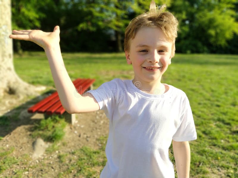A White Boy of 7 Years Old with Blond Hair and Gray Eyes Raises His Right  Hand and Smiles. Child in a White T-shirt Stock Photo - Image of  background, little: 190825258