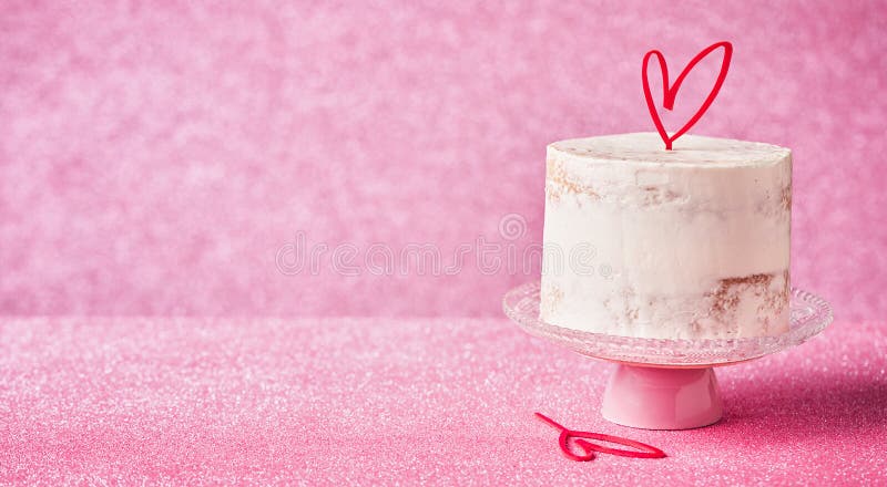 White Cake decorated with heart cake topper, against a pink glossy background, banner with copy space. Romantic love concept.