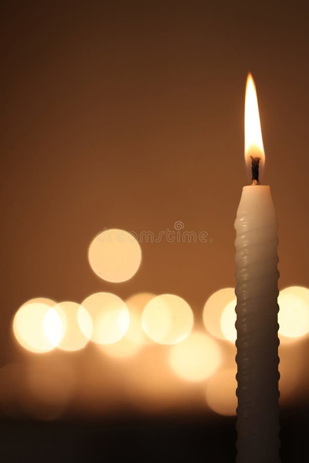 White candle on dark bokeh background. White candle on dark bokeh background