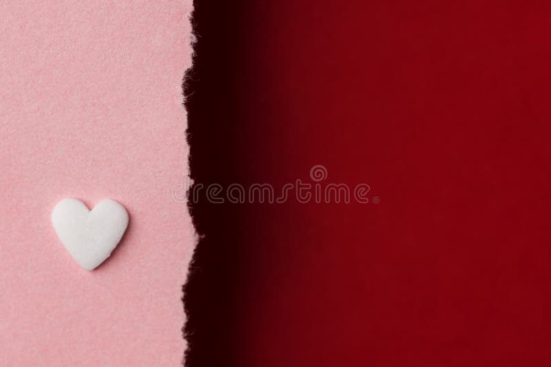 White candy heart on duotone pink burgundy red paper background with torn edge. Valentine women`s mother`s day charity