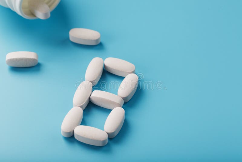 White Capsules with Vitamins in the Form of B Poured from a Jar on a