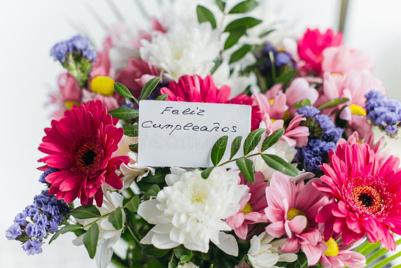 White card for a bouquet with the inscription happy birthday in spanish Feliz Cumplea os in a bright beautiful bouquet of flowers