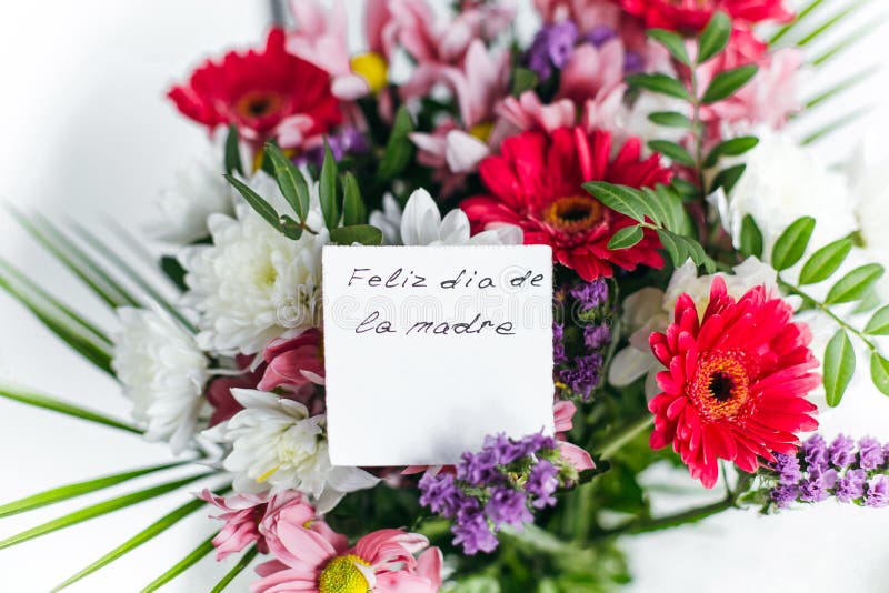 Card for a bouquet with the inscription Happy Mother`s Day in spanish in a bright beautiful bouquet of flowers. White card for a bouquet with the inscription royalty free stock photography