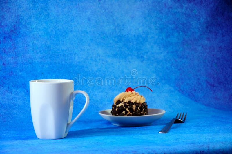 White ceramic mug of hot tea and a plate with chocolate biscuit cake with cherry and cream. Close-up stock images White ceramic mug of hot tea and a plate with chocolate biscuit cake with cherry and cream. Close-up stock images