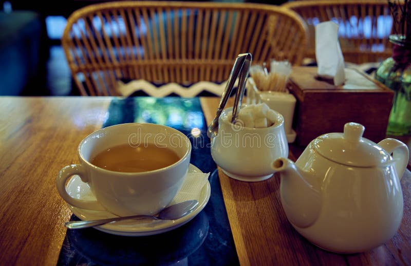 White Ceramic Tea Set. Cup with Green Tea, Teapot and Sugar Bowl on Restaurant Table Stock Photo
