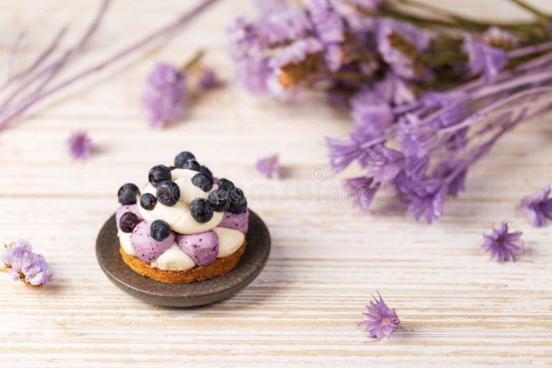 White chocolate and blueberry sable tartelette on a white drift wood table with purple dry flowers background royalty free stock image White chocolate and blueberry sable tartelette on a white drift wood table with purple dry flowers background royalty free stock image