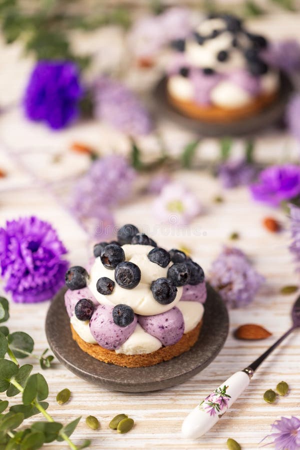 White chocolate and blueberry sable tartelette with vintage spoon on a white drift wood table with purple dry flowers background. stock images White chocolate and blueberry sable tartelette with vintage spoon on a white drift wood table with purple dry flowers background. stock images