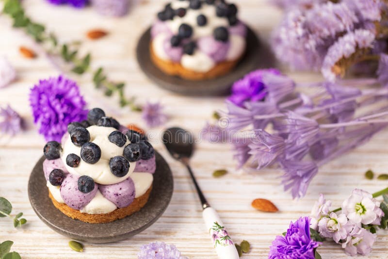 White chocolate and blueberry sable tartelette with vintage spoon on a white drift wood table with purple dry flowers background royalty free stock photography White chocolate and blueberry sable tartelette with vintage spoon on a white drift wood table with purple dry flowers background royalty free stock photography