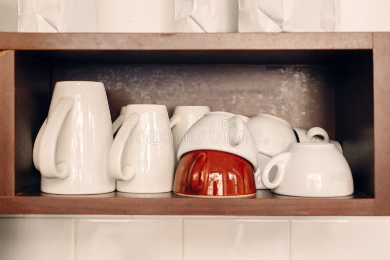 White coffee cups stacked on shelf in coffee shop