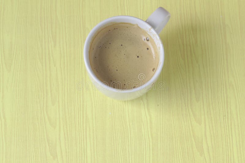 White coffee mugs morning light On the floor of a yellow wooden table Coffee bubbles in a clean, clean glass Breakfast. Placed in royalty free stock images White coffee mugs morning light On the floor of a yellow wooden table Coffee bubbles in a clean, clean glass Breakfast. Placed in royalty free stock images