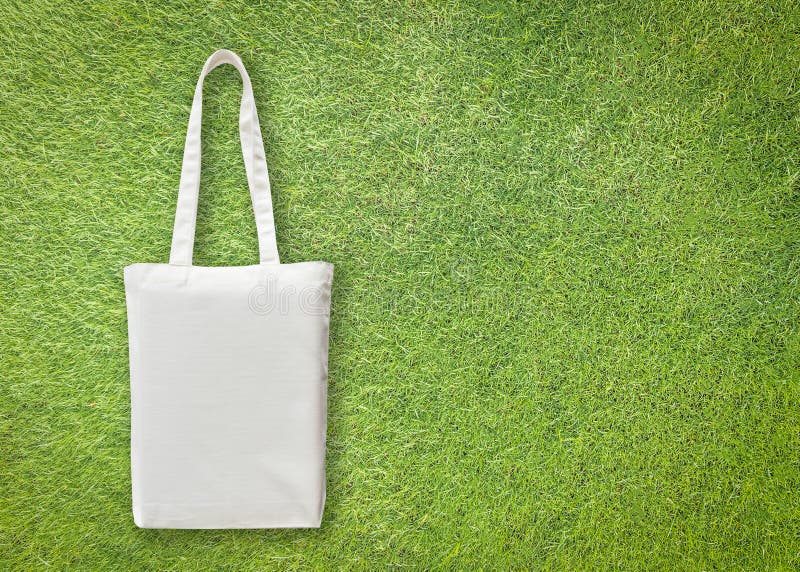 White cotton canvas eco shopping bag mock up with handle isolated on green grass lawn  background for handbag fashion accessory
