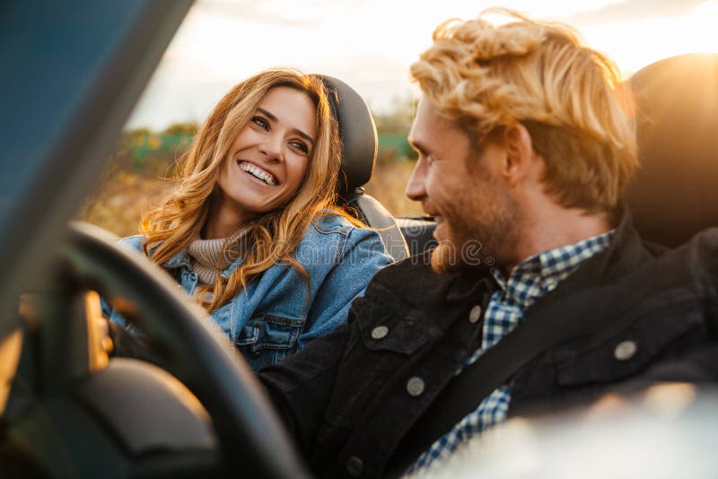 White couple smiling together while driving in car during trip