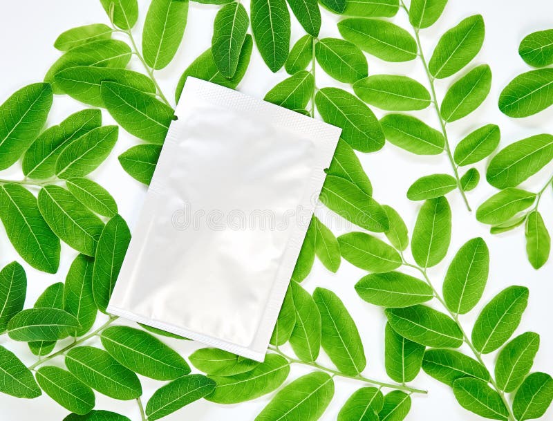 White cream bag on blank label package for mock up on a green leaves background. The concept of natural beauty products