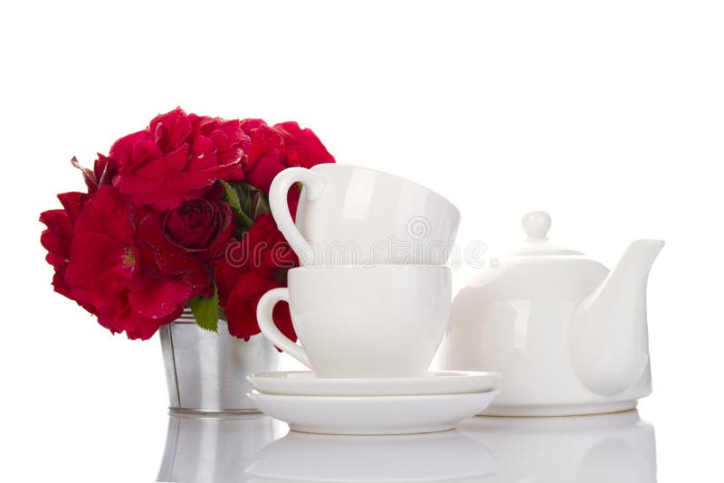 White crockery for tea and a bouquet of roses