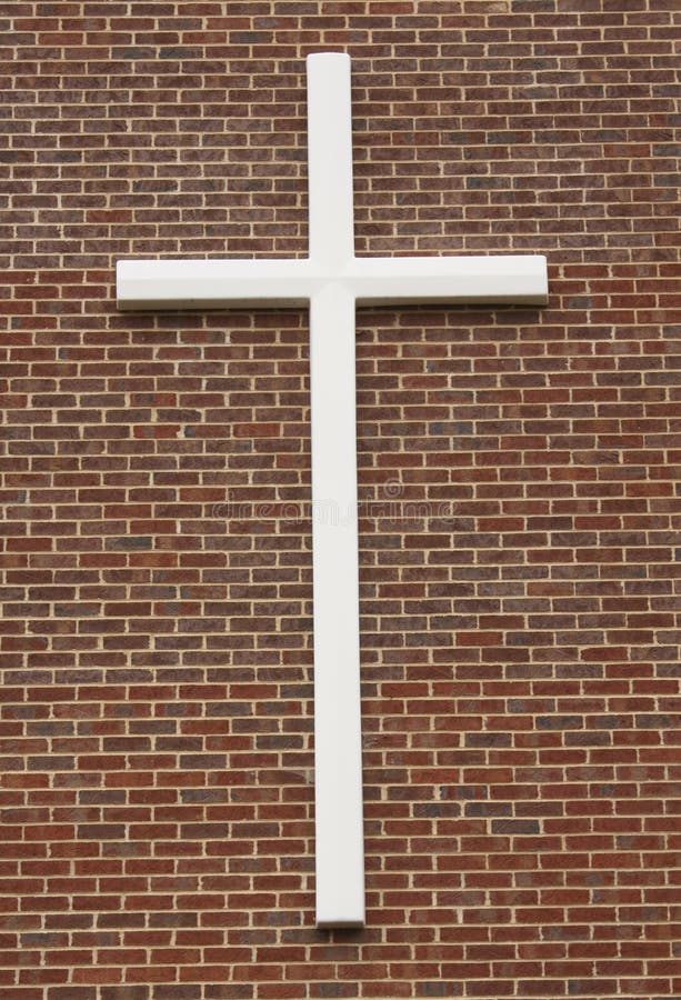 Close up of white crucifix attached to brick wall building. Close up of white crucifix attached to brick wall building.