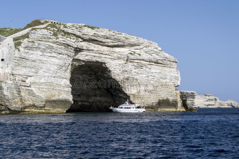 White cruise ship in front of a rock formation with a cave near Bonifacio port stock photos White cruise ship in front of a rock formation with a cave near Bonifacio port stock photos