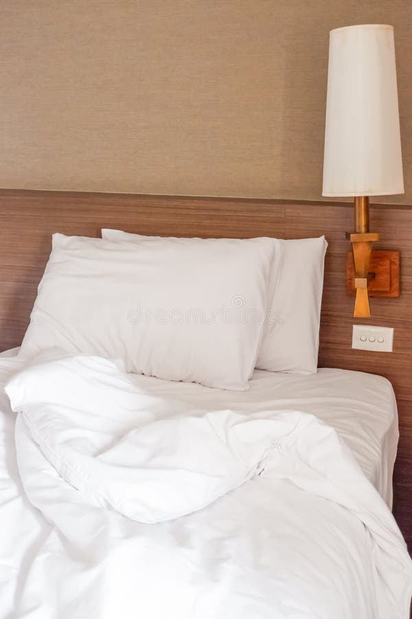 White Crumpled Bed Sheet and Two Messy Pillows in a Hotel Room Stock