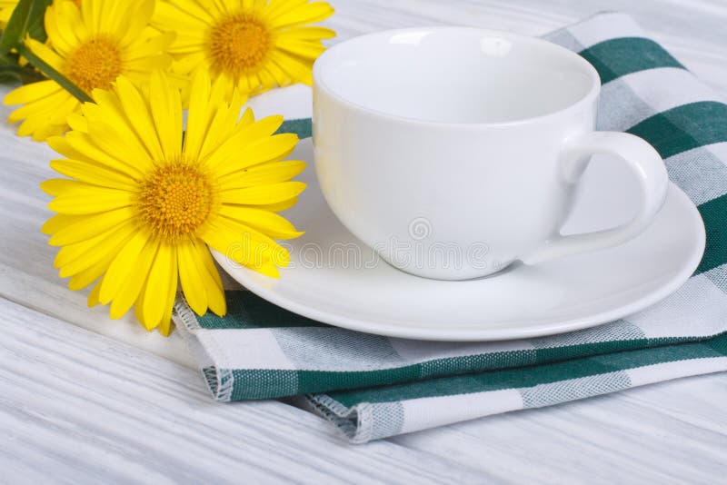 White cup and saucer with bouquet of daisies