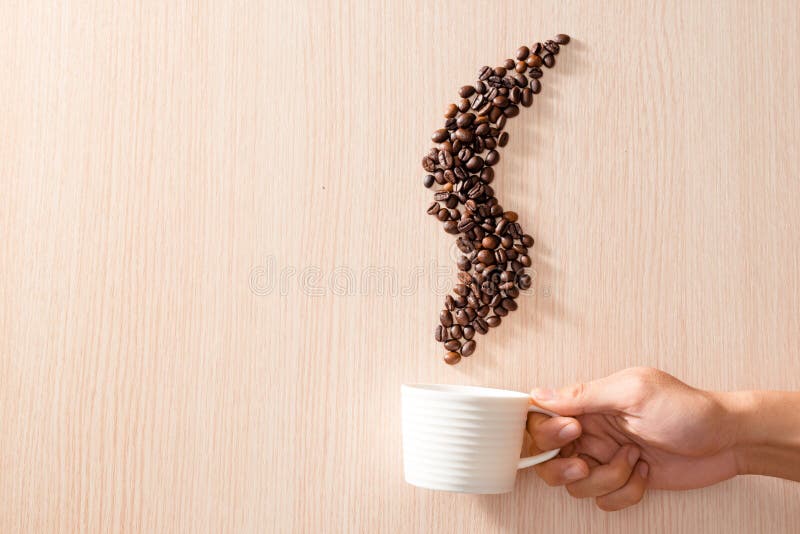 A White Cup with Smoke Shape Coffee Beans on Wooden Background Stock
