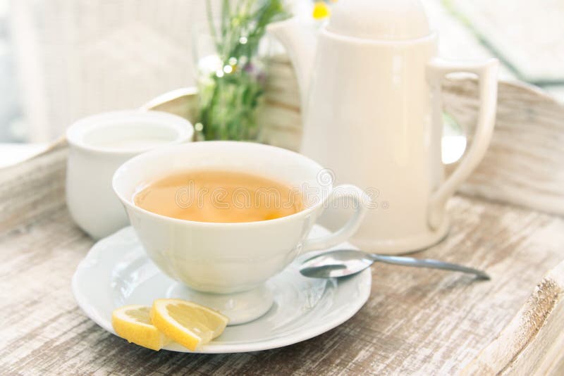 White cup of tea on vintage table composition