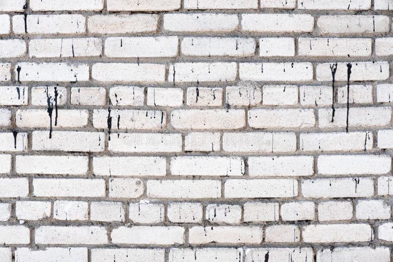 White dirty brick wall texture background. Wall with poured black paint. Old, weathered and cracked bricks close up. Copy space