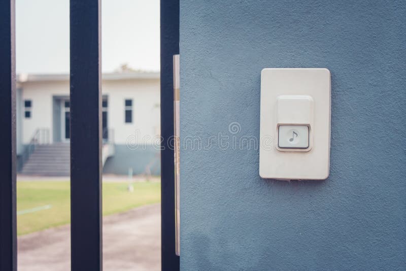 White doorbell or buzzer button on concrete wall beside doorway with house in the background. royalty free stock photos White doorbell or buzzer button on concrete wall beside doorway with house in the background. royalty free stock photos