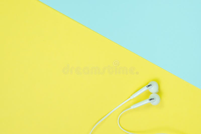 White Earphones or ear buds small talk on sweet blue and yellow colour pastel paper, top view, texture and background. music listening concept idea.